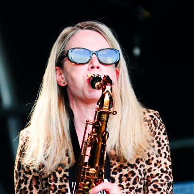 Liz Mitchell playing alto saxophone in leopard print jacket