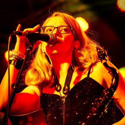 Liz Mitchell singing at microphone in sequined dress