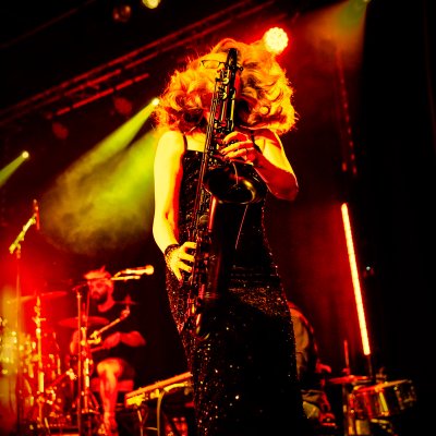 Liz Mitchell playing saxophone on stage with drummer